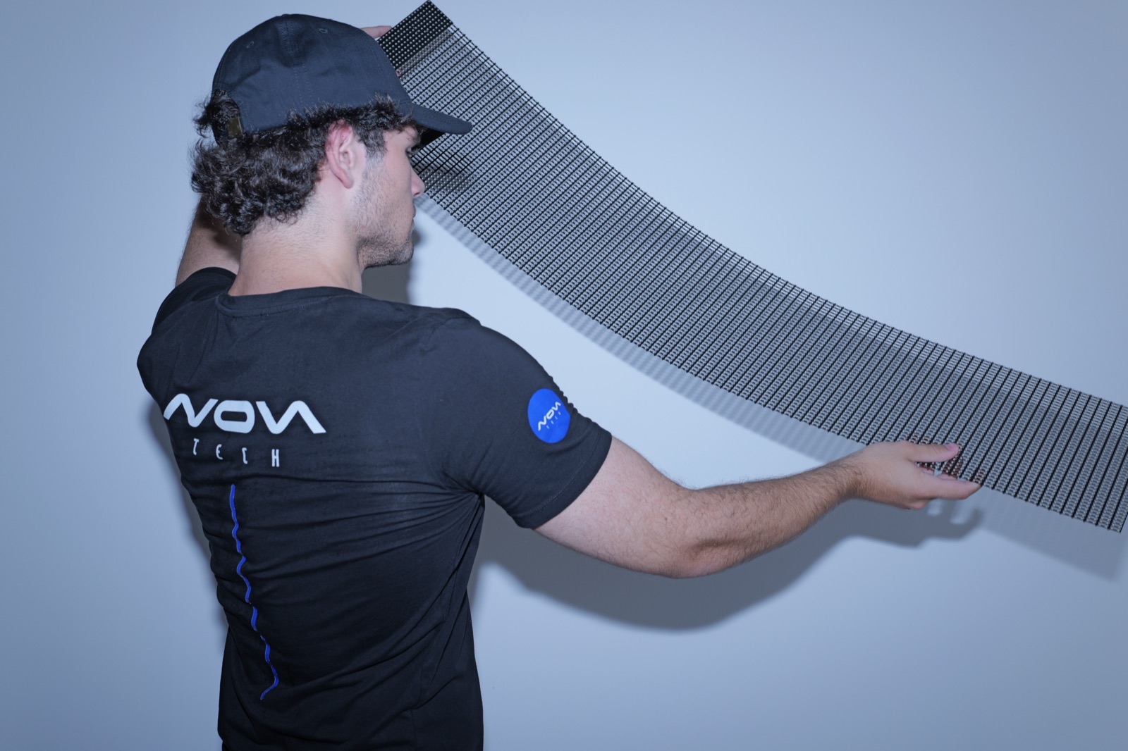 The mesh curved into a deep bend held in both hands, showing how far it flexes without damage